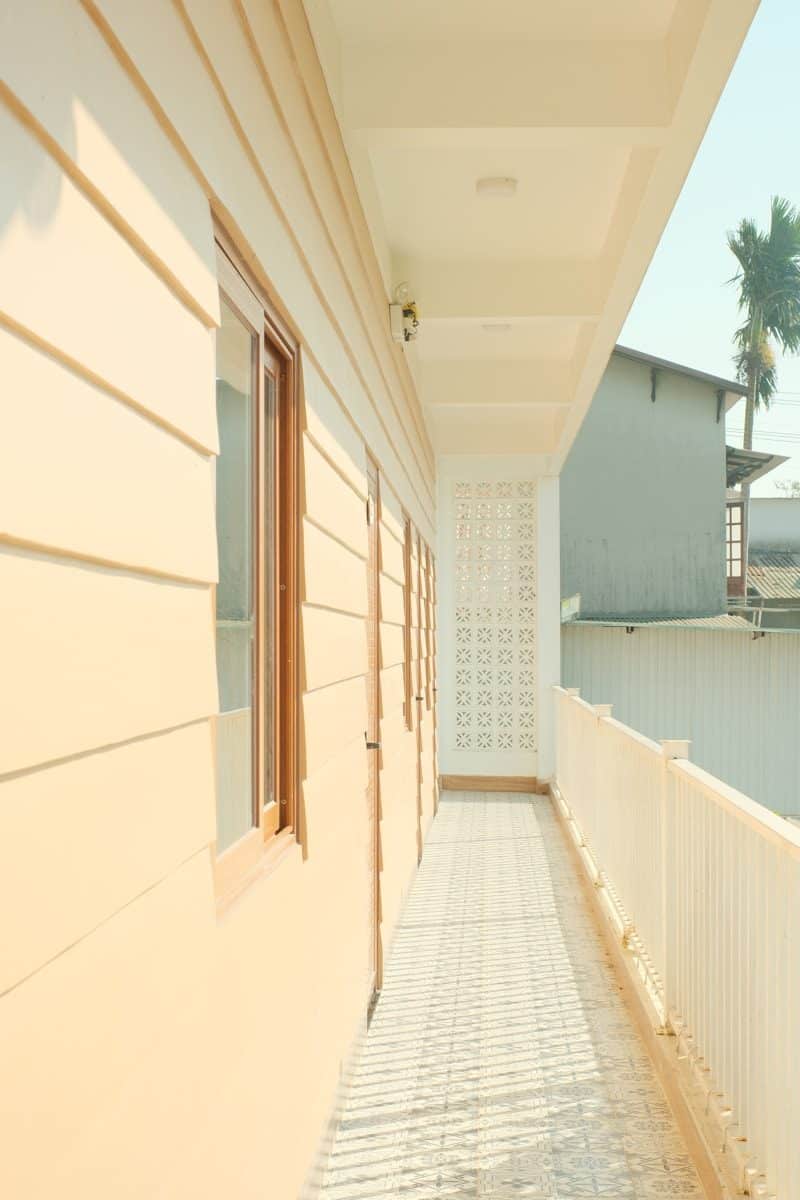 A light-colored building with a long balcony and windows.